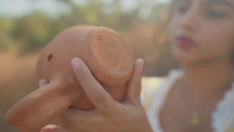 up-close-of-a-young-woman-holding-and-intently-looking-at-a-broken-clay-cup