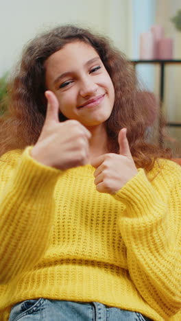 happy child kid girl looking approvingly at camera showing thumbs up like positive sign good news