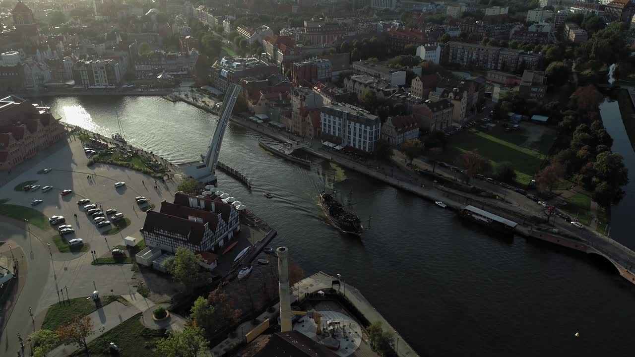 Aerial View Of A Baltic Ship Sailing On Motlawa River Passing By The Wartka Bridge In Gdansk, Poland At Sunrise