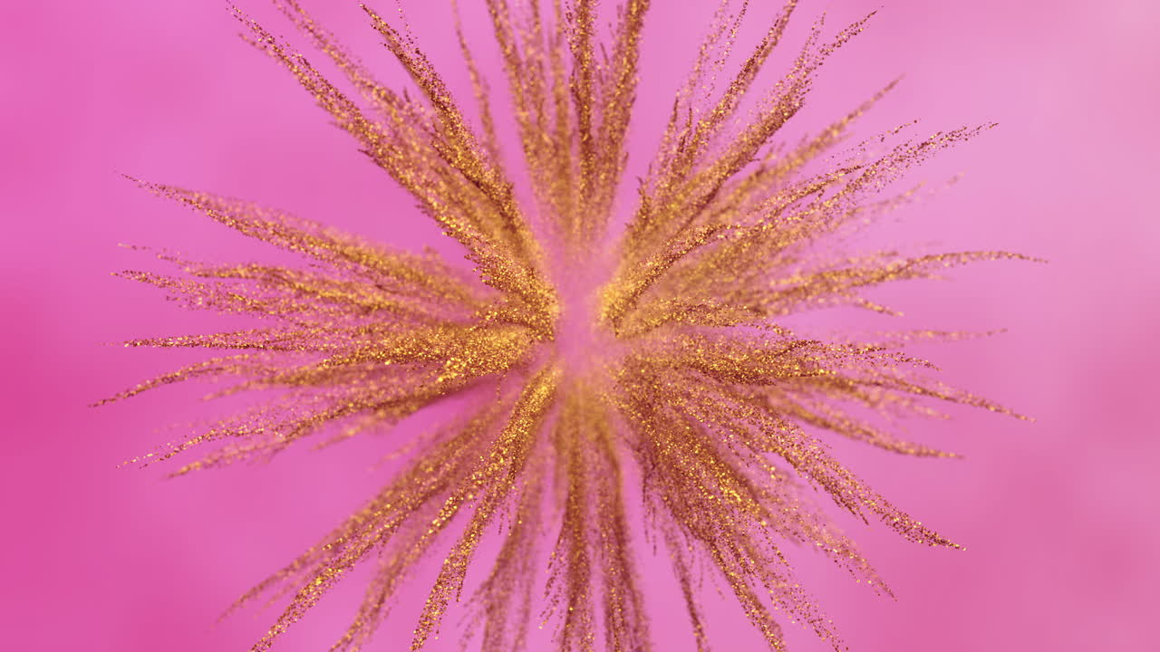 Particelle di glitter dorato che esplodono e si diffondono su sfondo rosa