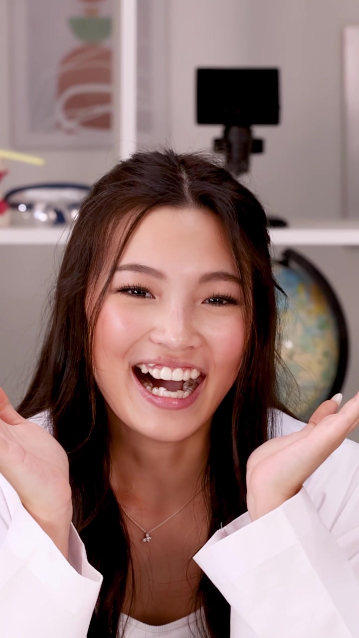 Cheerful student in white lab coat laughs during science class in a bright classroom.