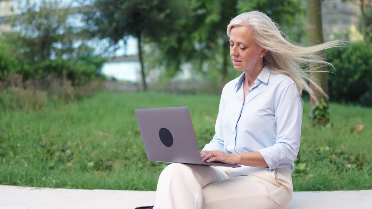 Senior Businesswoman Working on Laptop in Park