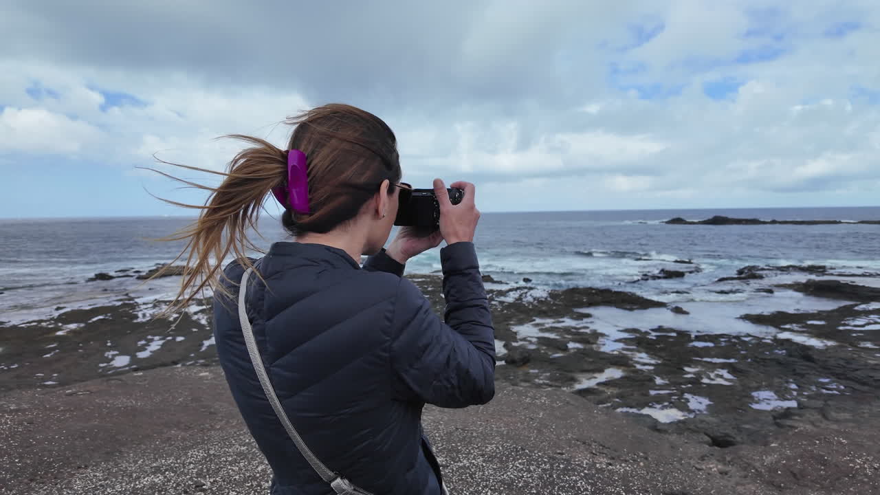 Woman taking pictures of a rocky coastline in Fuerteventura