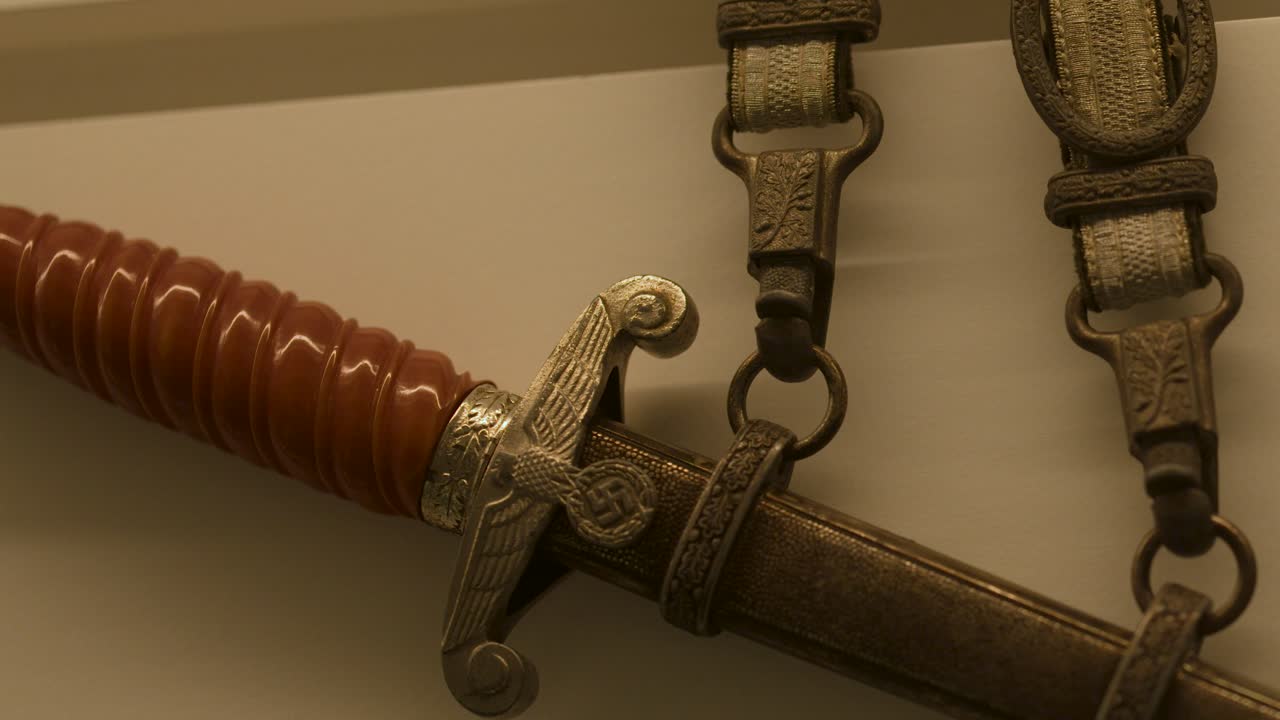 Detailed close-up pan of German officer’s dagger, museum exhibit lighting, Dunkirk, France, static camera