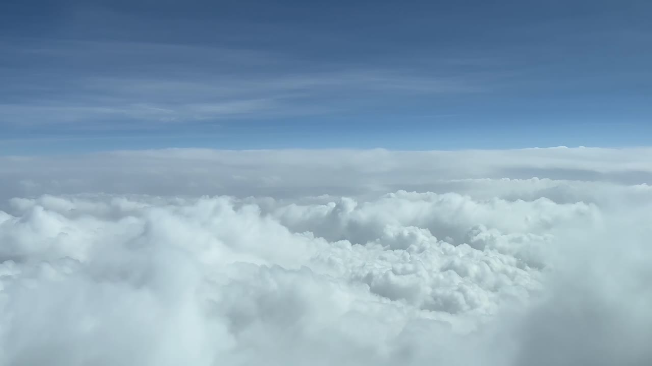 Himmeludsigt fra et jetcockpit i marchhøjde over skyer.