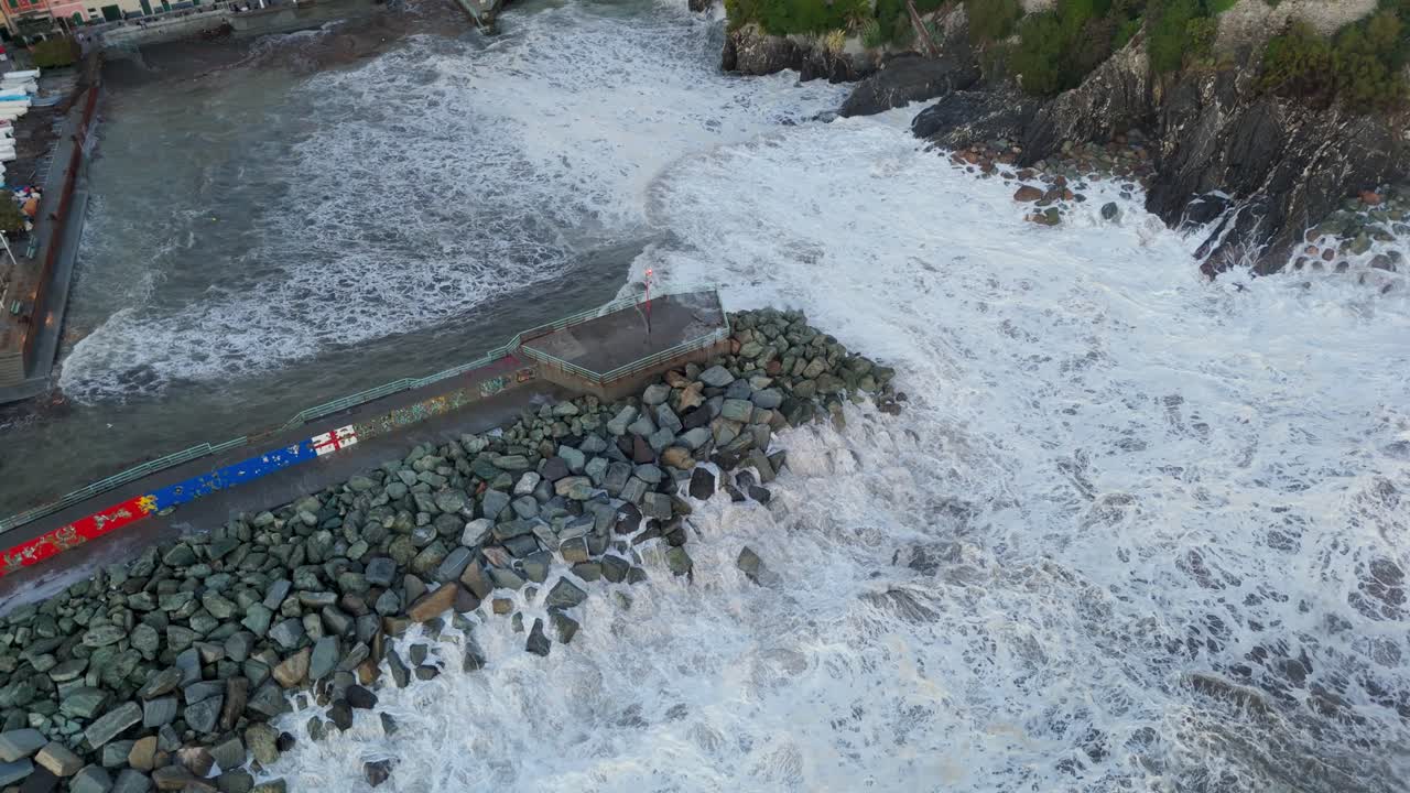 Huge foamy sea waves crashing on stony harbor pier wave breaker, Genoa