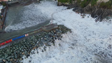 Huge-foamy-sea-waves-crashing-on-stony-harbor-pier-wave-breaker,-Genoa