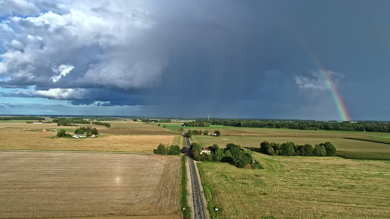 rural agriculture fields with storm clouds and rainbow on background. aerial wide view