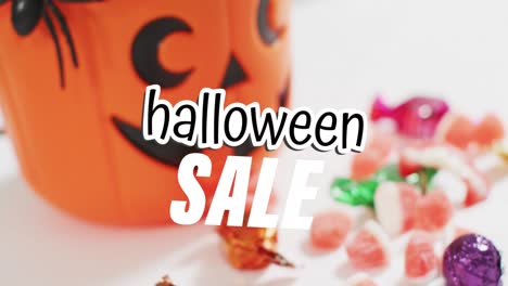 animation of halloween sale text over carved pumpkin bucket with sweets on grey background