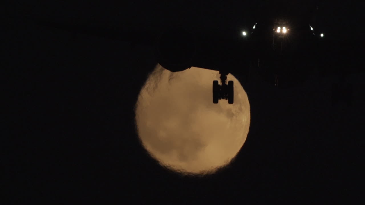 Airplane Silhouetted Against a Full Moon at Night