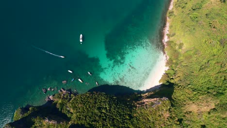 aerial top down view of a boat motoring through beautiful turquoise blue water in the andaman sea arriving at ko kai island in krabi thailand on a sunny summer day with pristine white sand beaches