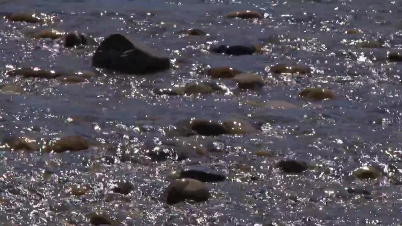 L'acqua bassa del fiume scorre su rocce lisce in una giornata di sole splendente