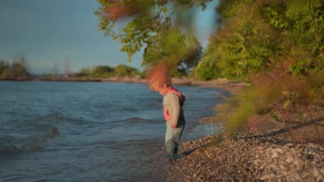 Kleiner-Junge-Steht-Im-Wasser-Am-Strand-Und-Sieht-Zu,-Wie-Die-Wellen-Hereinkommen,-Dann-Geht-Er-Weg