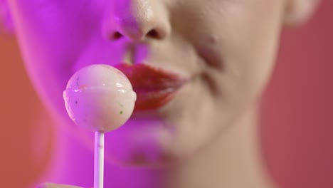 Chica-Lamiendo-Paletas-Con-Seducción,-Primer-Plano-De-La-Boca-Sobre-Fondo-Rojo.