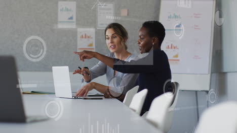 Animation-of-graphs,-loading-bars-and-circles,-diverse-female-coworkers-discussing-reports-on-laptop