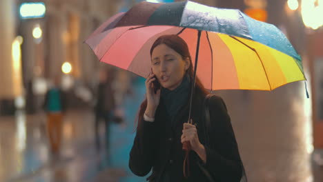 brunette woman talks on the phone on the street on rainy day