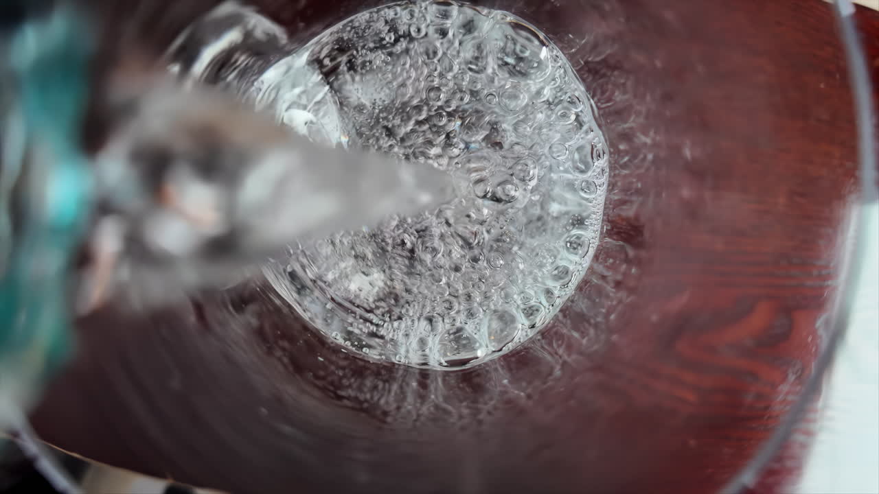 Slow motion pouring of mineral water on a glass close pu