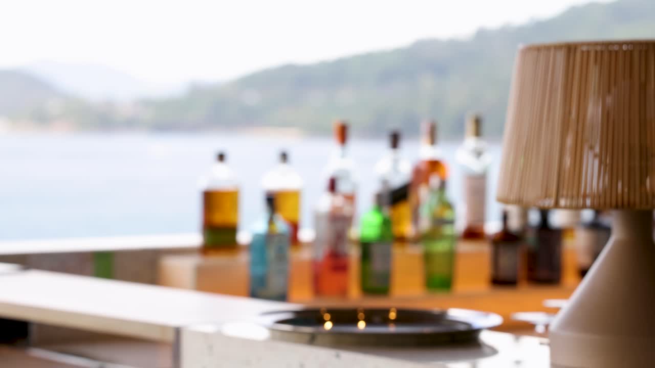 A serene beach bar setting with blurred bottles and a lamp, overlooking the sea in Phuket, Thailand