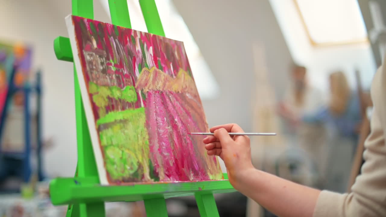 A woman painting a picture using a brush in a studio. Slow motion