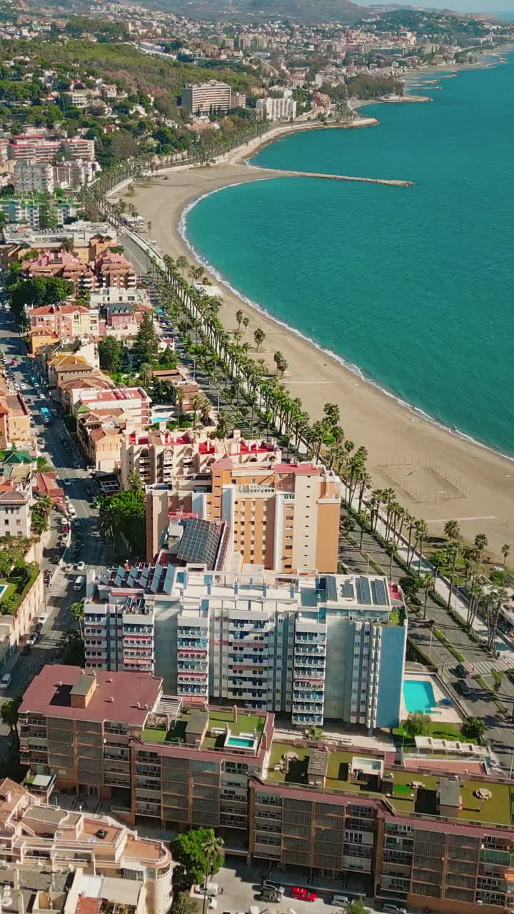 Panoramica aerea verticale di edifici residenziali costieri nella baia della spiaggia della Malagueta, Malaga, Spagna