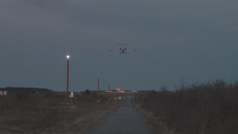 a jet lands at dusk, viewed from the end of the runway