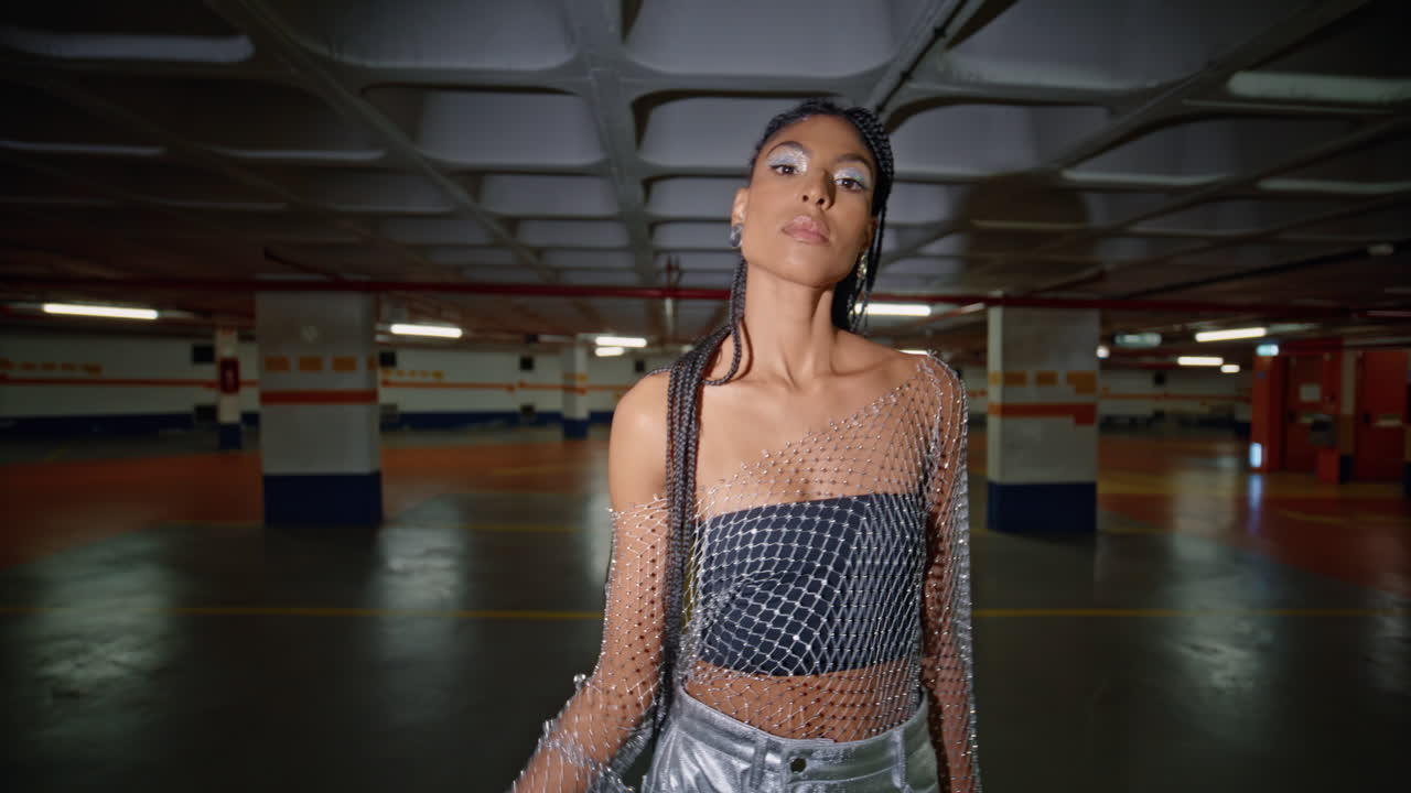 mujer mirando a la cámara caminando en el estacionamiento oscuro retrato. morena posando