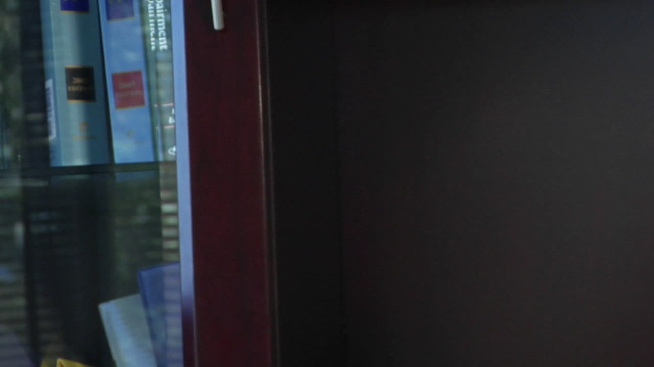 un primer plano de un hombre sonriendo junto a su colección de libros