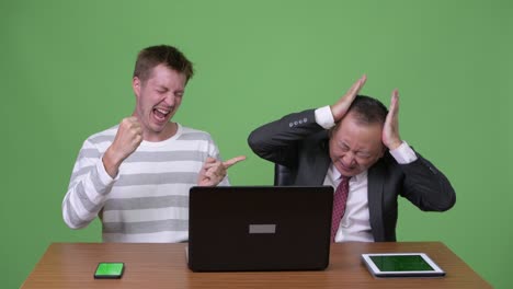 mature japanese businessman and young scandinavian businessman working together