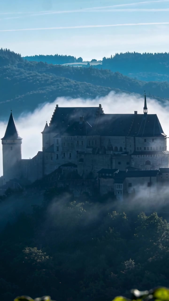 Video verticale: Brezza mattutina che solleva la nebbia, rivelando la guglia e il tetto di un castello per annunci di viaggio
