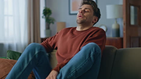 tired man choosing channel relaxing home sofa after hard day close up. bored guy