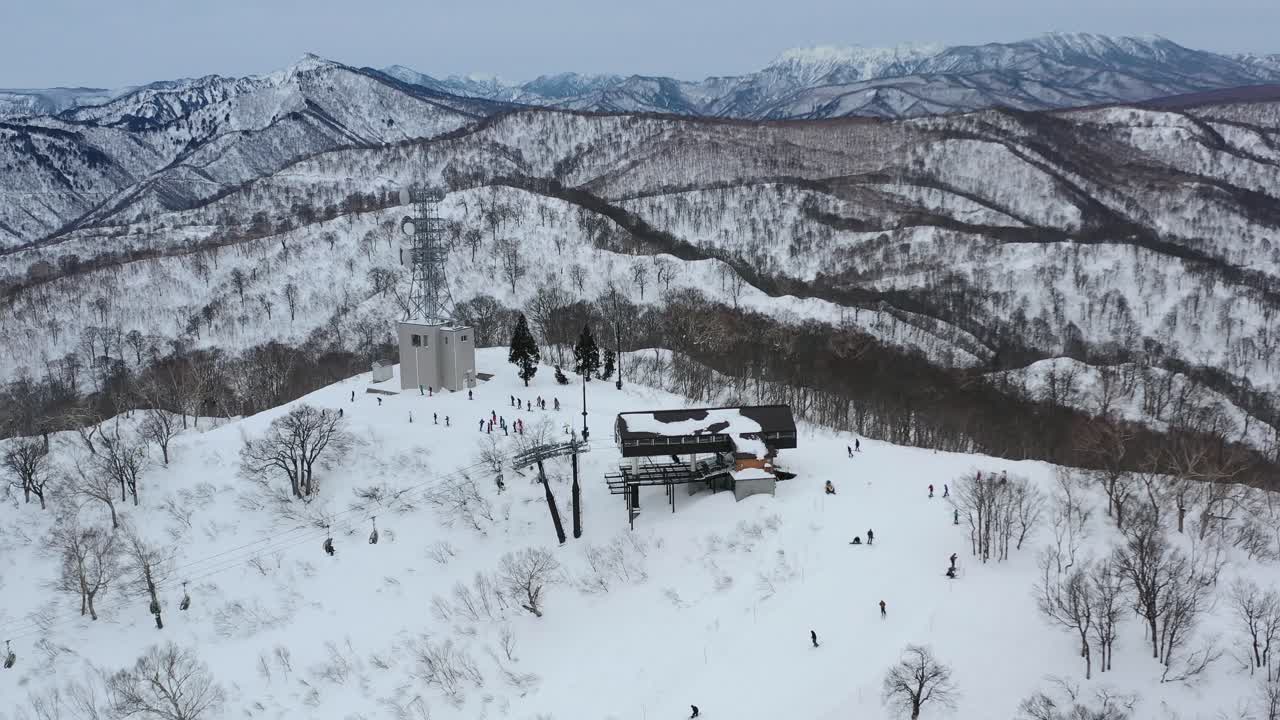 esquiadores en remonte que llegan a la pendiente del pico de la montaña nevada en invierno en nozawa onsen en nagano, japón