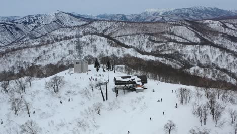 skiers on ski lift arriving at snowy mountain peak slope in winter at nozawa onsen in nagano japan