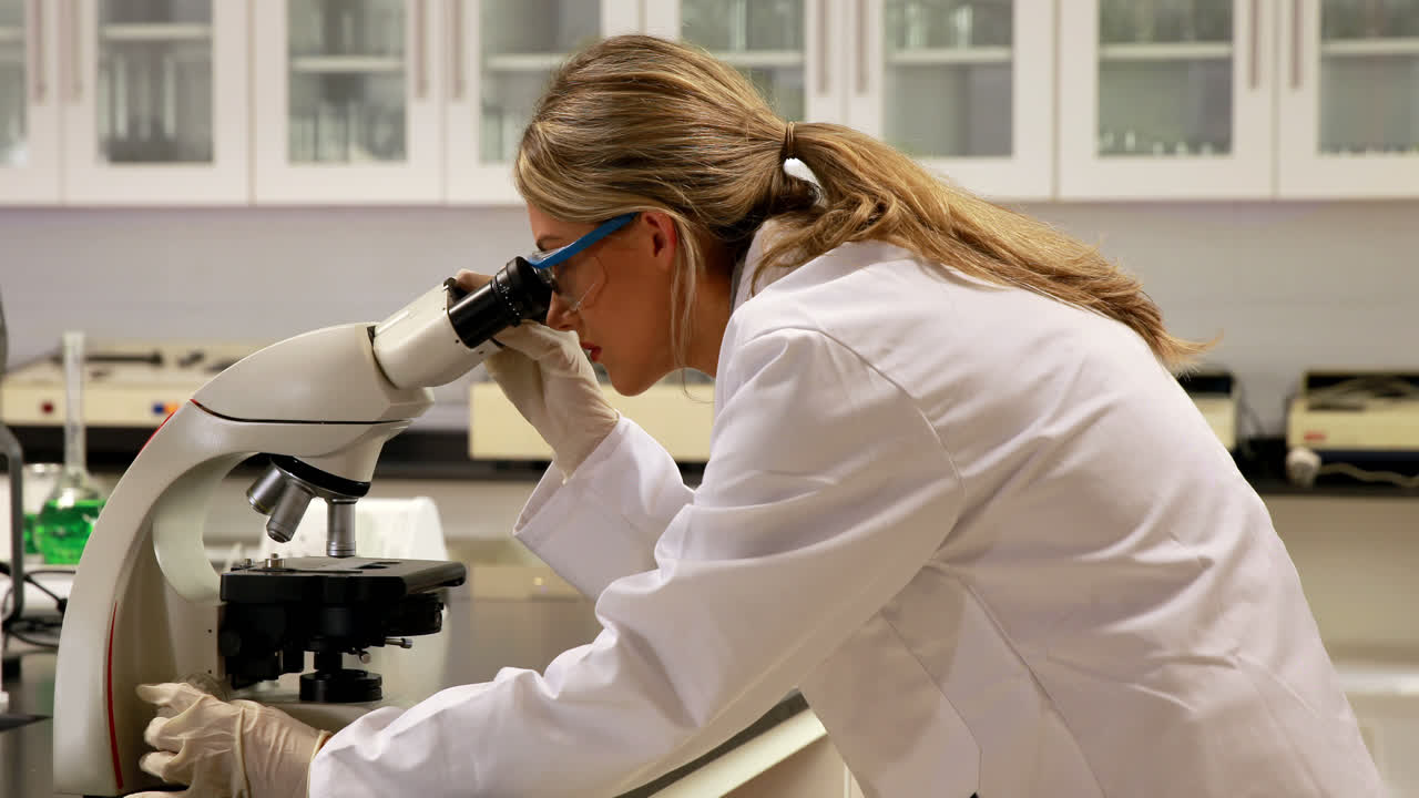 Young scientist looking through microscope in the lab