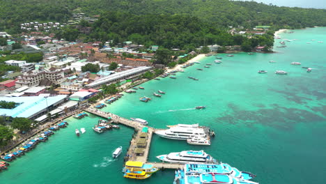 koh phi phi island harbor with moored boats and docked ferries, aerial tilting upward