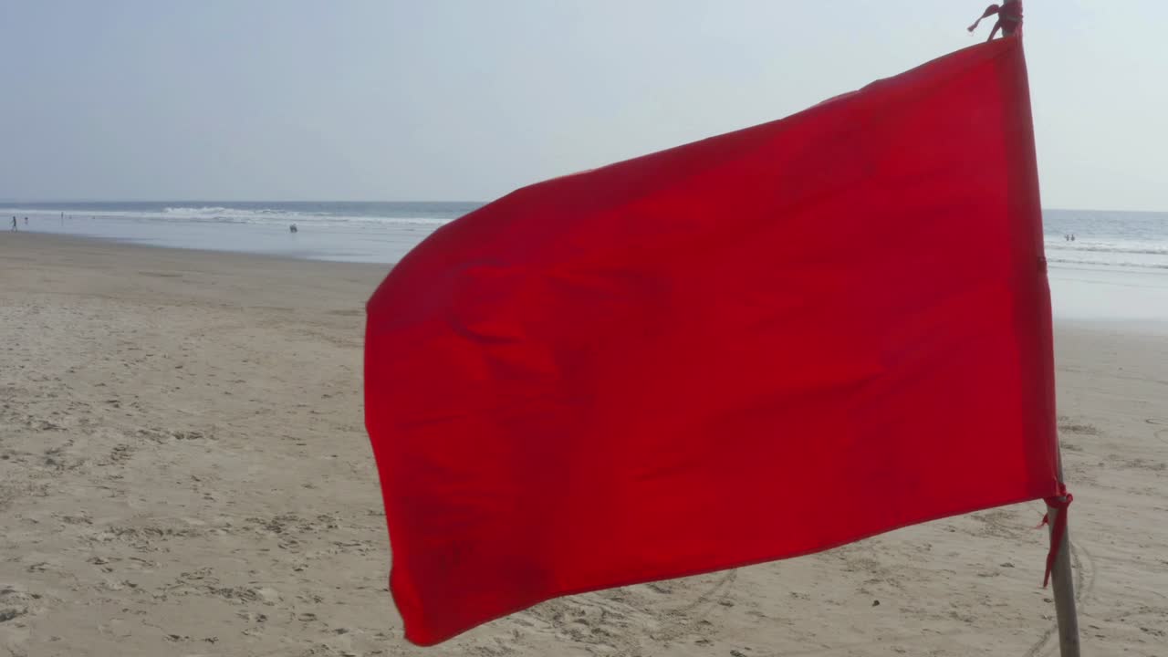 cerca de una bandera roja brillante con playa y océano en el fondo
