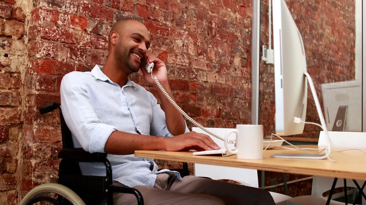Homme d'affaires occasionnel en fauteuil roulant travaillant à son bureau