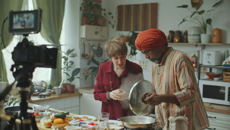 female food blogger and indian chef filming culinary vlog in kitchen