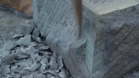 primer plano de mano de un artesano de piedra cancagua usando un pico para dar forma a una gran pieza de piedra en la ciudad de ancud en la isla de chiloé