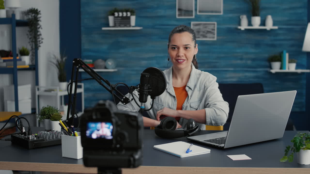 Attractive social media influencer sitting at home studio desk while getting ready for live broadcast