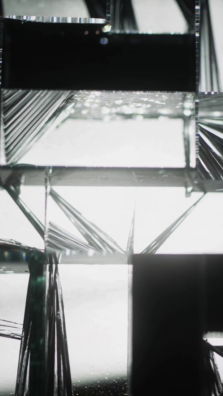 Vertical video: Panning camera revealing stacked glass prisms on lightbox for crystal inspection
