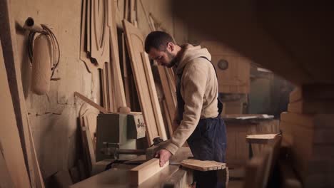 Craftman-in-a-blue-overalls-cuts-the-rail-on-a-circular-saw-and-turns-off-the-machine.-Slow-motion.-Workshop