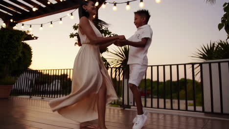 mother and son dancing on a terrace at sunset