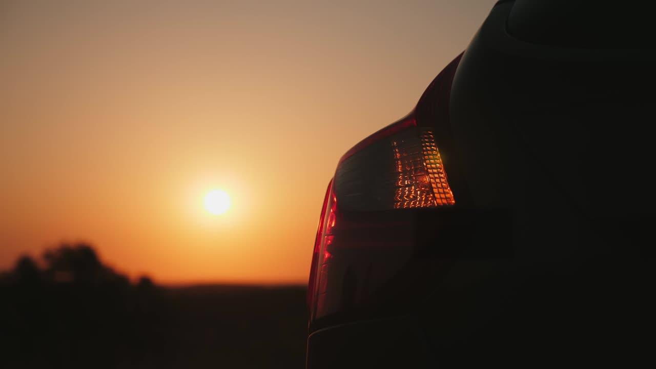 автомобиль мигает аварийными огнями при заходе солнца.