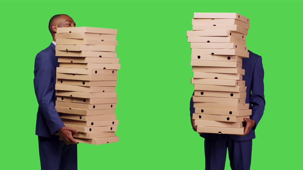 Two men carrying stacks of pizza boxes on green background