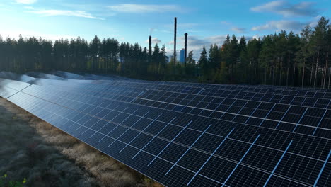 aerial view over a solar field with power plant background, sunny fall day