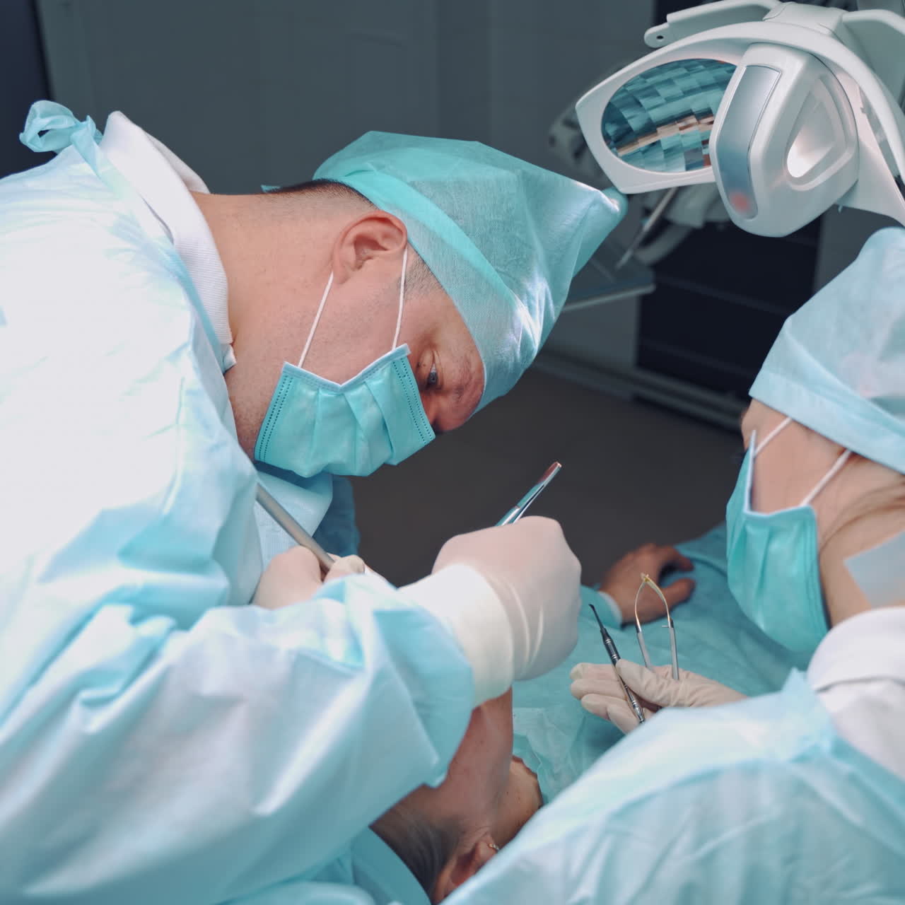 Specialist man and female assistant in blue medical uniform are working in dental office. Professional dentist and a nurse make an operation on teeth for client. Oral treatment.