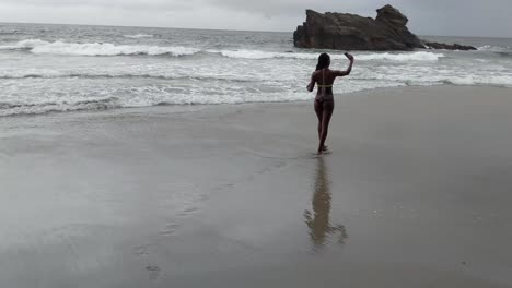 sexy bikini model walking into the ocean while taking selfies of her buttocks