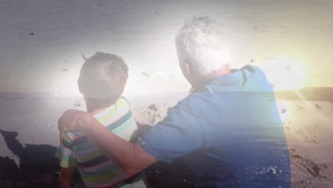 animation of glowing light over senior man with his grandson on beach