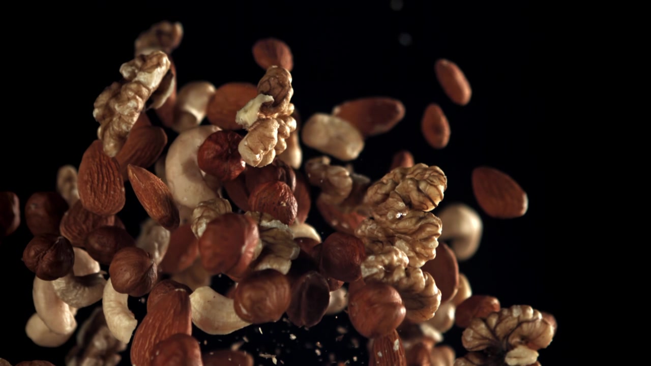 Various Nuts Falling in Slow Motion Against Black Background
