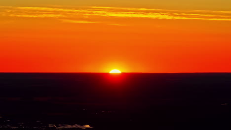 sunset above flat horizon with vivid orange and red sky during dusk, drone video
